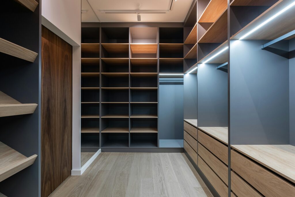 Interior of modern spacious wardrobe room with empty shelves near door and mirror